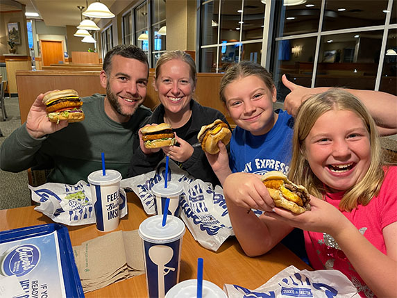 A family smiles with CurderBurgers in hand.